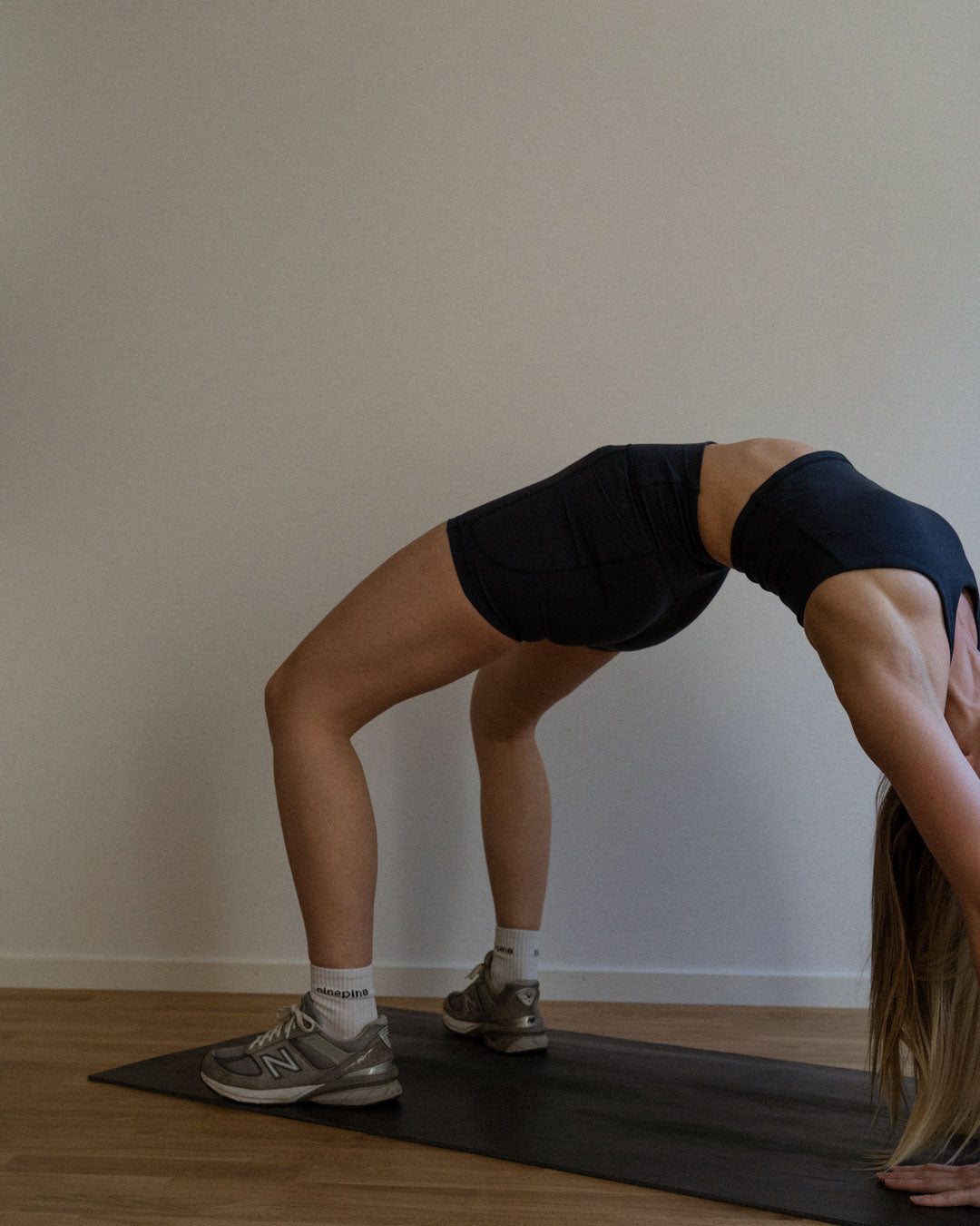 Woman in Ninepine sports bra and biker shorts performing a yoga bridge position